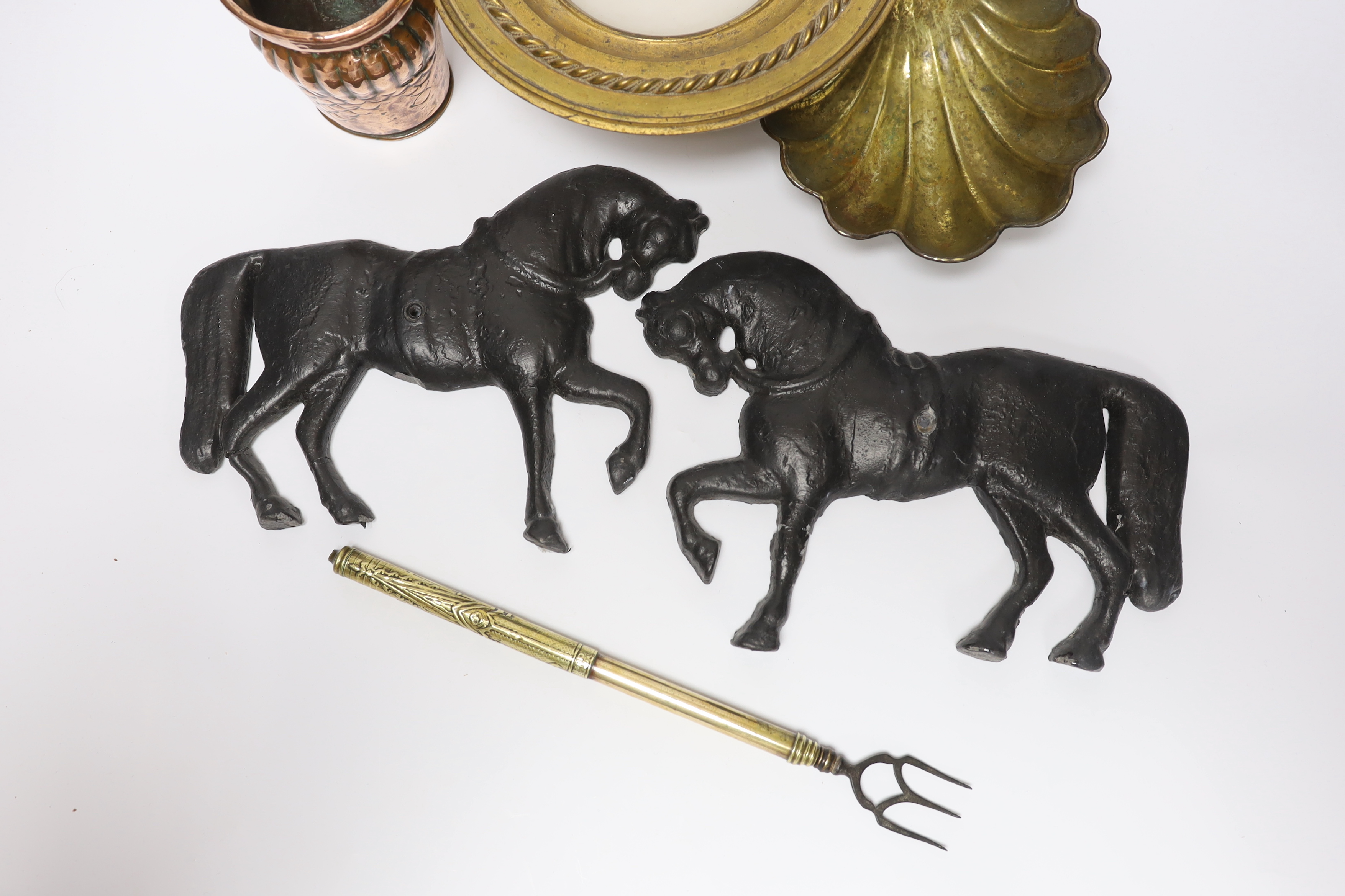 A group of metalware to include a pair of lead ‘horse’ wall mounts, a copper wall pocket, a, brass ‘scallop shell’ dish, a telescopic three pronged fork and an alabaster pedestal dish